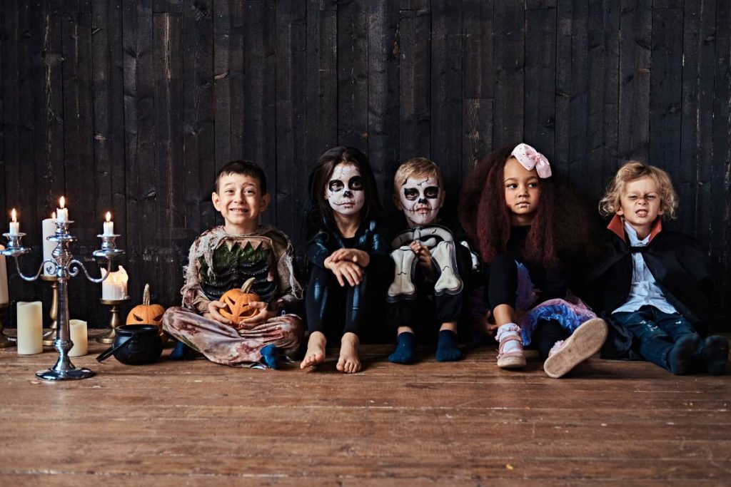 Halloween party with group children who sitting together on a wooden floor in an old house.